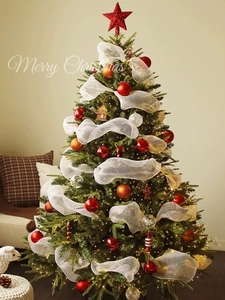 Decorated Christmas tree with red star topper, gold baubles and white mesh ribbon detail