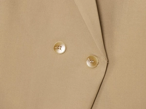 Detailed macro view of khaki blazer sleeve featuring two elegant buttons and premium fabric