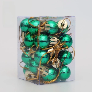 Close-up of shiny green Christmas ornaments in a clear box with golden hanging strings