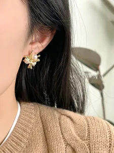 Close-up of 18k gold plated pearl earrings in vintage branch design worn by a model