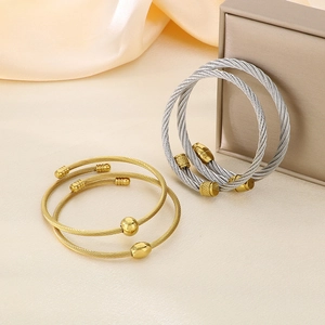 Detail of twisted steel wire cable bracelet in gold and silver finish on silk
