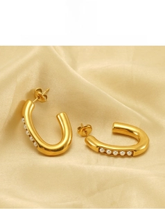 Close-up of gold-plated U-shaped earrings with white pearls on a silk background