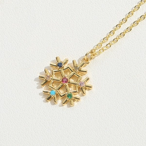 Detailed close-up of a golden snowflake necklace with vibrant multicolor gemstones on a white background