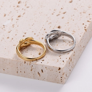 Minimalist knot rings in gold and silver finish on a travertine stone pedestal