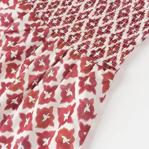 Detail shot of red floral print fabric featuring smocked elastic texture on white textile