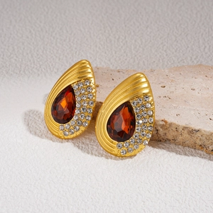 Detailed macro view of vintage gold teardrop earrings featuring deep orange gemstones