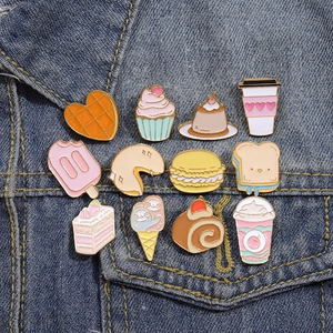 Vue détaillée de douze épingles en émail colorées en forme de desserts sur une veste