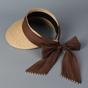 Detail of straw sun visor with dark brown ribbon bow and white faux pearl charms