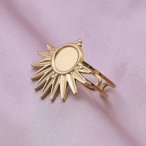 Minimalist gold stainless steel sunburst ring with oval bezel on purple silk background