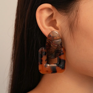 Close-up of model wearing geometric resin earrings in tortoise shell and brown tones