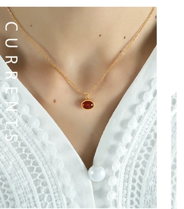Detail of a vintage red agate pendant on a gold titanium steel chain worn by a model
