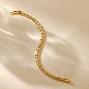 Close-up of a 14K gold plated woven chain bracelet featuring a sleek S-curve design