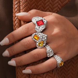 Silver textured ring set with colorful resin gemstones worn on a hand holding a bag