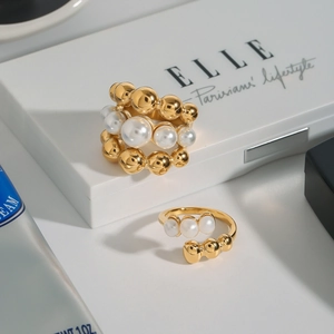 Detail of gold-plated stacked and open rings with white pearls on a display box