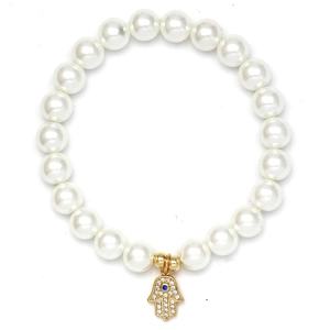 Macro shot of white pearl bracelet with gold Hamsa hand charm and blue evil eye detail