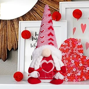 Close-up of Valentine gnome plush with red heart hat and white braids in festive decor