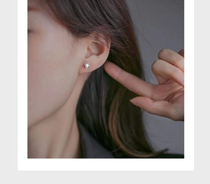 Close-up of a minimalist silver stud earring with a square zircon on a female model
