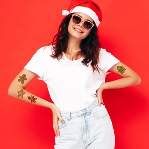 Christmas gingerbread temporary tattoos featuring snowflakes and candy on arm with red background