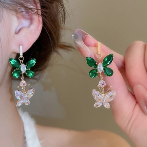 Detailed close-up of double-layer butterfly earrings with green and clear zircons