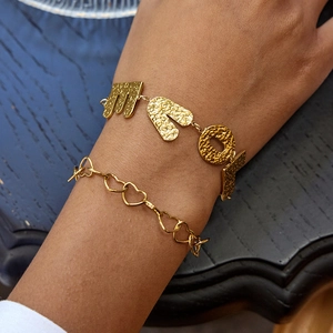 Close-up of golden hammered LOVE letter bracelet and hollow heart chain on wrist