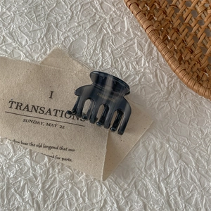 Detailed shot of a translucent dark grey acetate hair claw with golden Handmade script
