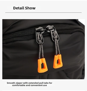 Detail of smooth double zippers with extended orange non-slip pulls on black sling bag