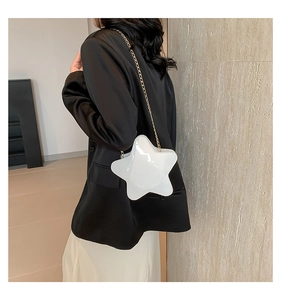 Star-shaped white crossbody bag with gold chain strap shown on model in black suit