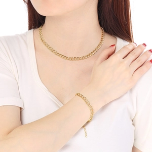 Close-up of a gold stainless steel curb chain necklace and bracelet set on a model