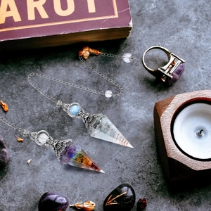 Macro shot of 7 chakra resin pendulums with silver metal caps on dark tarot theme background