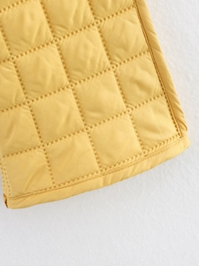 Detail of yellow quilted jacket showing diamond stitching and fine fabric texture