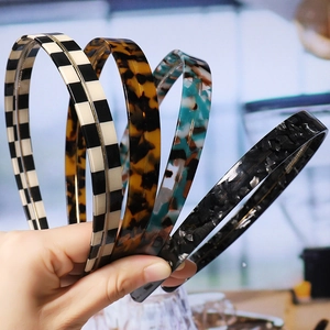 Hand holding four stylish headbands with checkered and marble patterns in a group display