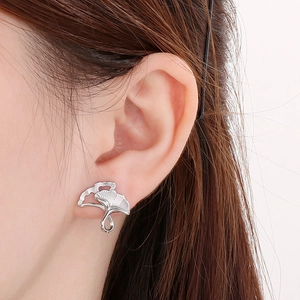Detailed close-up of a silver ginkgo leaf earring with intricate hollowed textures