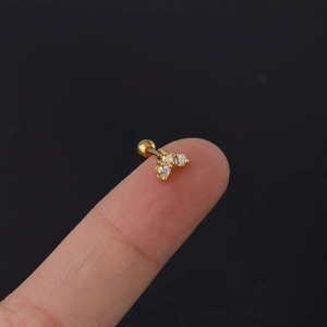 Macro view of a tiny golden heart stud with iridescent zircons and screw ball back