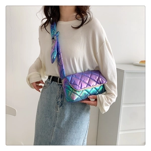Close-up of iridescent purple quilted crossbody bag with wide strap worn by a model