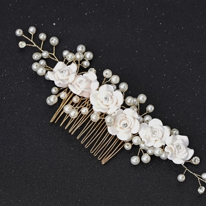 Close-up of golden bridal hair comb with white ceramic roses, pearls and rhinestones
