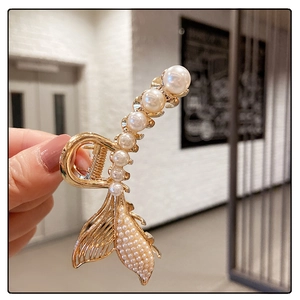 Detailed shot of golden fishtail hair claw clip with elegant large white pearls