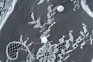 Vue détaillée de la dentelle florale blanche et des boutons en tissu de la robe