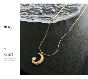 Detailed macro view of gold moon pendant featuring a sparkling round zircon stone