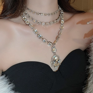 Detailed view of layered silver necklace with pear-cut crystals on a fashion model