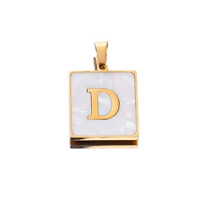 Macro shot of 22mm golden square pendant with white shell inlay and letter D engraving