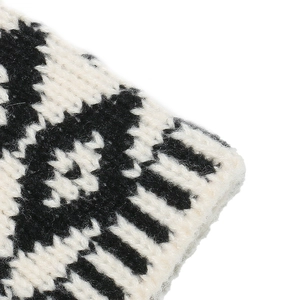 Close-up of geometric jacquard pattern on thick black and beige knitted beanie hat