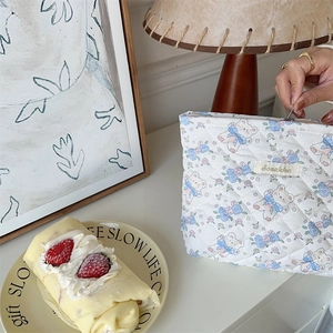 Quilted white cosmetic bag featuring cute bears and floral prints in a cozy setting