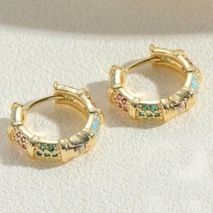 Detailed close-up of wide gold-plated hoop earrings with vibrant multi-colored crystals