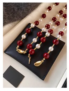 Dettaglio di perle di agata rossa e perle bianche con chiusura dorata su superficie ruvida