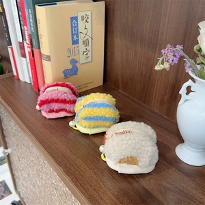 Macro view of plush macaron-shaped coin pouches with metal zippers and pearl accents