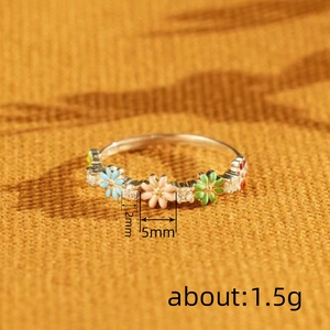 Floral enamel daisy ring with colorful flowers and zircons on a yellow knit background