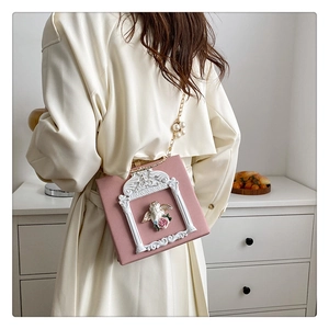 Detail of pink baroque handbag with angel relief, rose frame and pearl metal chain strap