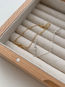 Detail of gold and silver S925 sterling silver woven heart knot bracelets in a wooden box