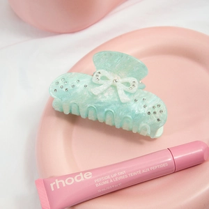 Detail of light green marble acetate hair claw with rhinestone bow on pink tray
