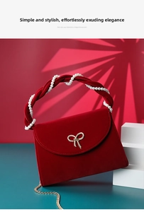 Detail of red velvet handbag featuring pearl-woven handle and golden bow clasp